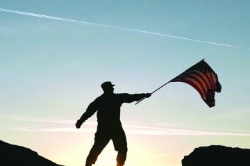 military servicemember holds a flag up